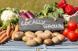 Organic vegetables on a stand at a farmers market with a sign reading locally grown Organic vegetables on a stand at a farmers market with a sign reading locally grown
