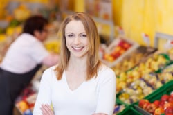 Smiling attractive young woman in a supermarket standing in front of the fresh produce display with her arms folded Smiling attractive young woman in a supermarket standing in front of the fresh produce display with her arms folded